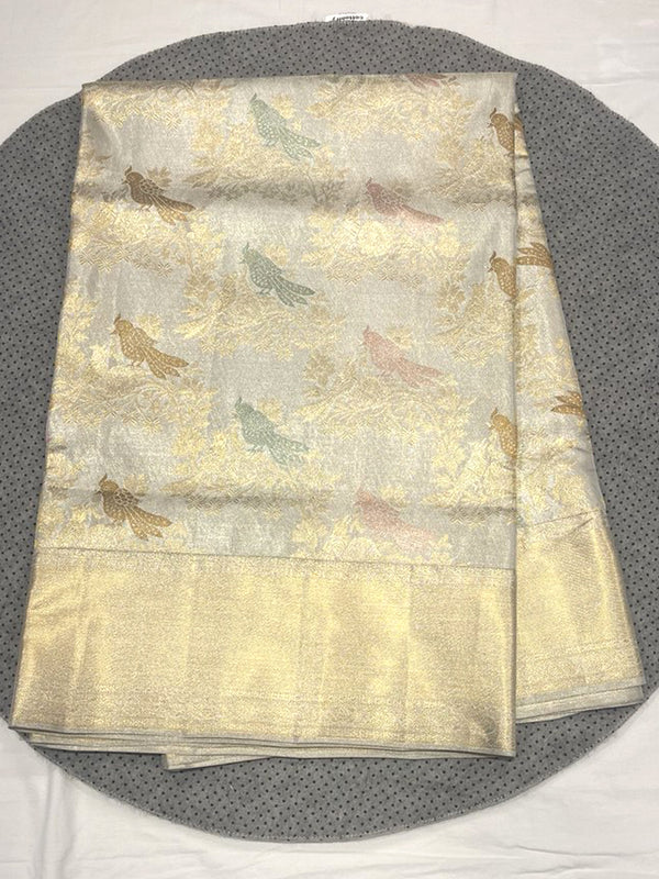 Luxurious Silver Tissue Kanjivaram Silk Saree with all-over woven Gold Zari bird (parrot) and floral motifs, finished with a luminous, wide, plain Gold Zari border.
