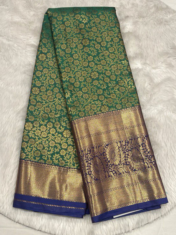 Emerald Green Kanjivaram Saree with all-over Gold Zari brocade, contrasted by a broad Navy Blue Zari border with paisley and floral panels.
